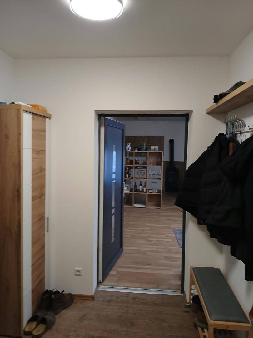Heller Eingangsbereich mit Holzboden, Garderobe und Blick in den Wohnbereich.