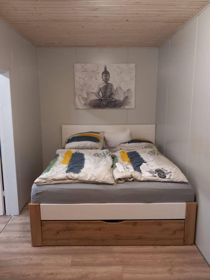 Schlafzimmer mit Holzbett, Stauraum und einer Buddha-Wanddekoration.