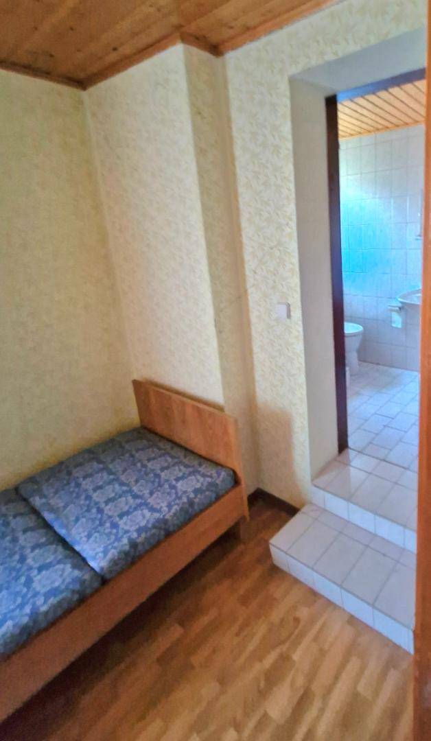 Schlafzimmer mit Bett, Holzdecke, Laminatboden und Stufen, die zu einem Badezimmer führen.