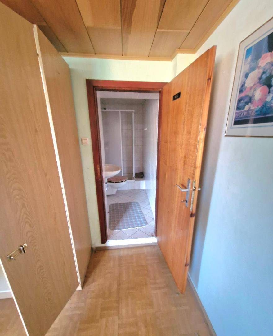Flur mit Laminatboden und Holztüren, der zu einem Badezimmer führt.