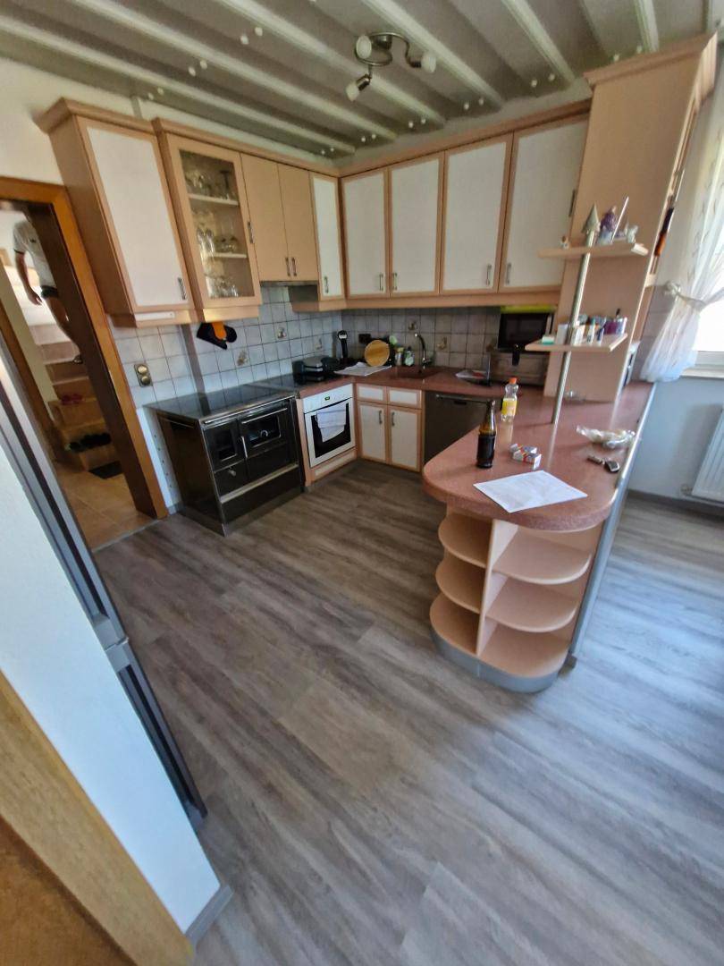Funktionale Küche mit hellen Schränken, Holzarbeitsplatte und Laminatboden.