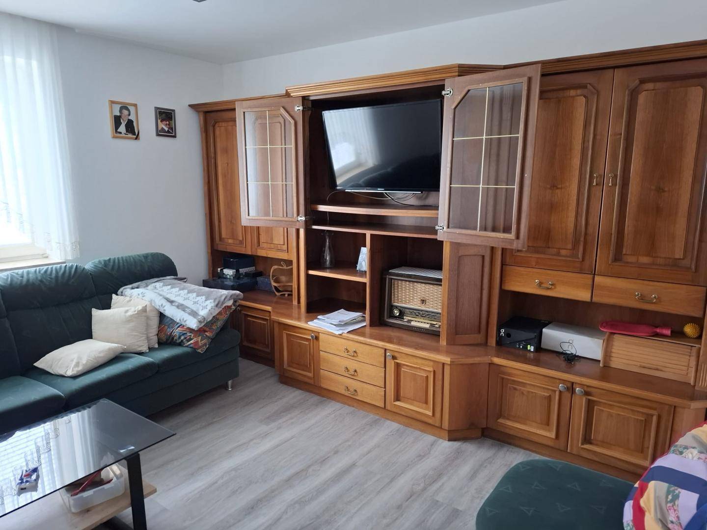Gemütliches Wohnzimmer mit traditioneller Holzschrankwand und Sofa.