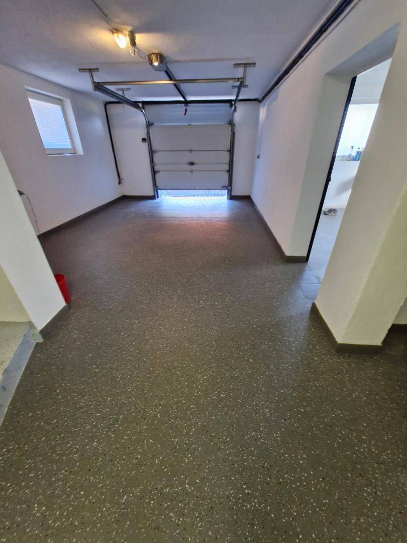 Innenansicht der Garage mit offenem Tor und Blick nach draußen.
