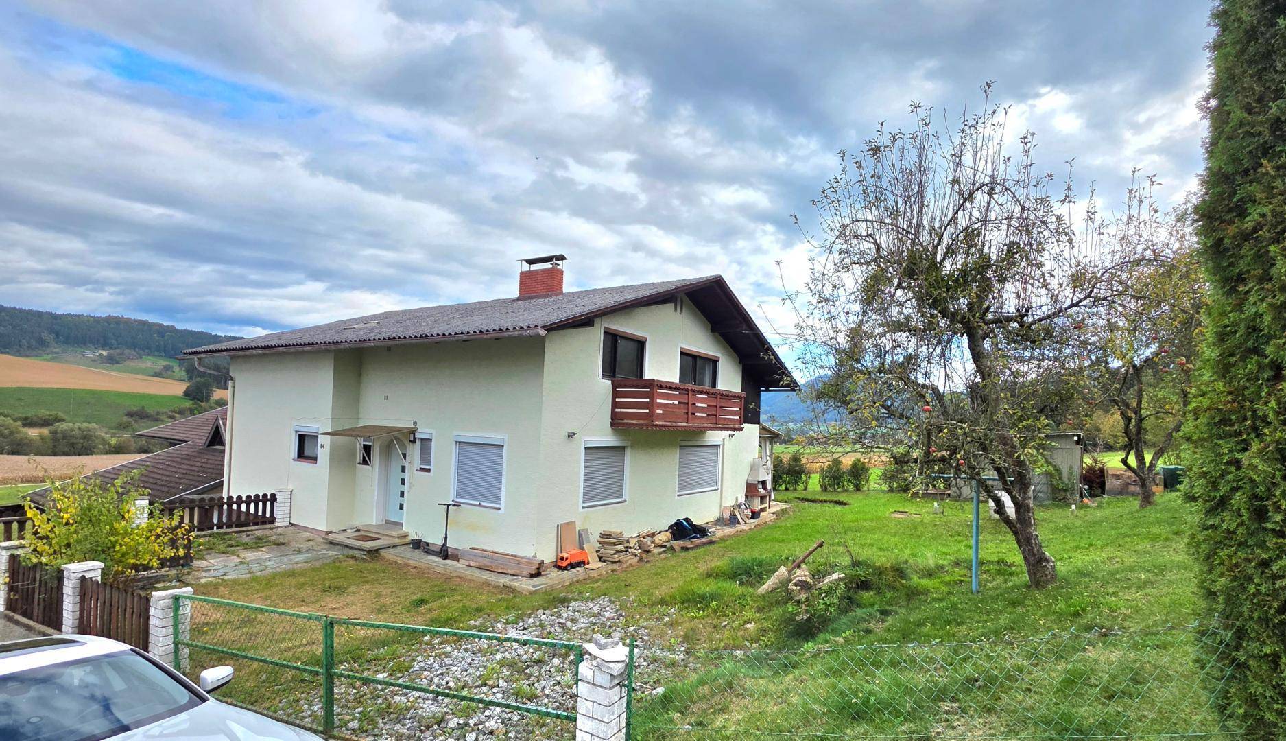 Rückansicht des Hauses mit großem Garten, Obstbäumen und weitem Blick auf die Landschaft.