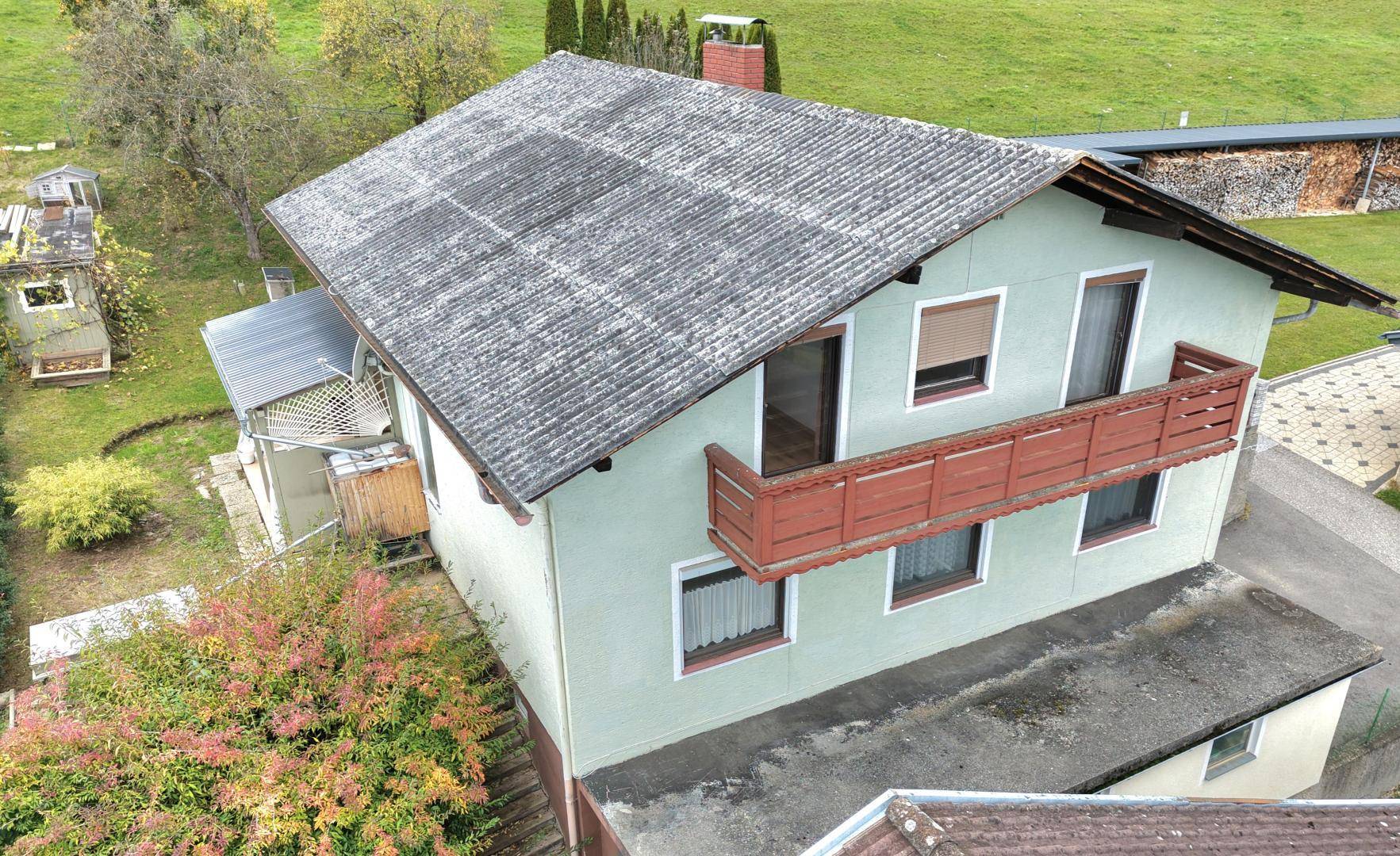 Seitenansicht des Hauses mit Balkon und Blick auf die umliegende grüne Landschaft.