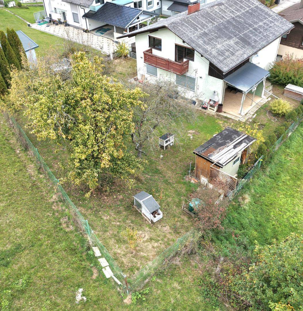 Gartenansicht von oben mit Obstbäumen, kleinen Tierställen und dem Haus im ländlichen Umfeld.