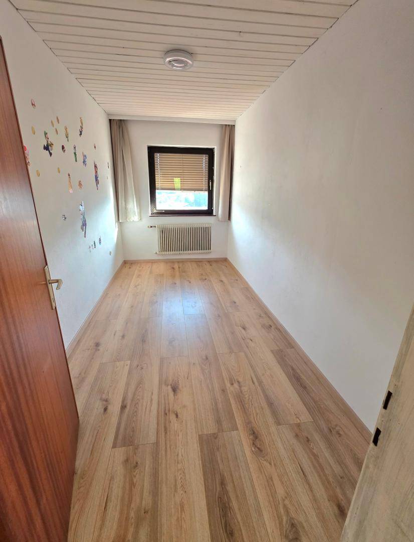 Schmaler Raum mit Laminatboden und Fenster, vielseitig nutzbar als kleines Zimmer.