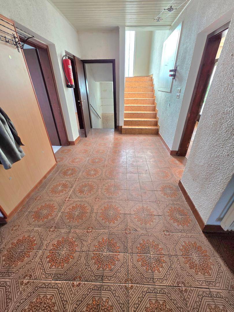 Geräumiger Flur mit gemusterten Fliesen, Holztreppe und Zugang zu verschiedenen Räumen.