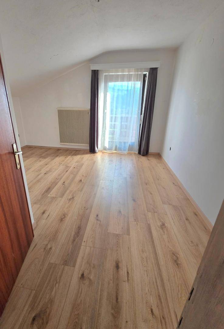 Helles Schlafzimmer im Dachgeschoss mit Laminatboden, großem Fenster und Dachschräge.