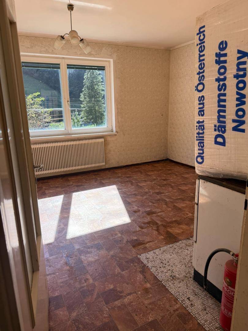 Raum mit gemusterter Tapete und Bodenbelag, ausgestattet mit Heizkörper und Fenster.