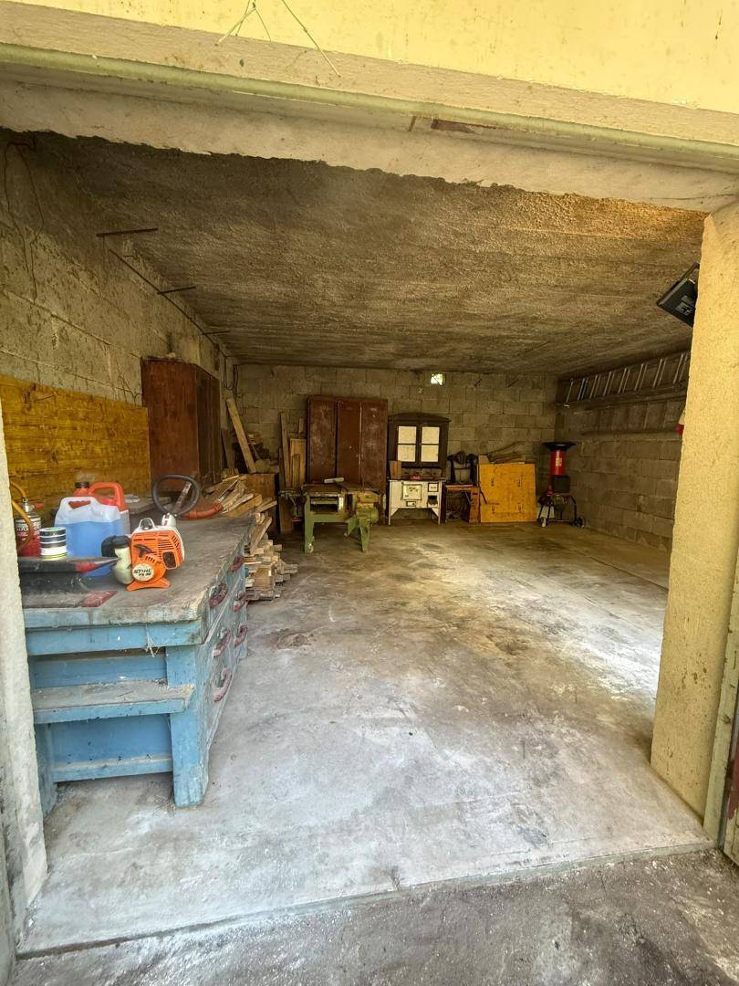 Geräumige Garage oder Werkstatt mit Betonboden und Werkbank.