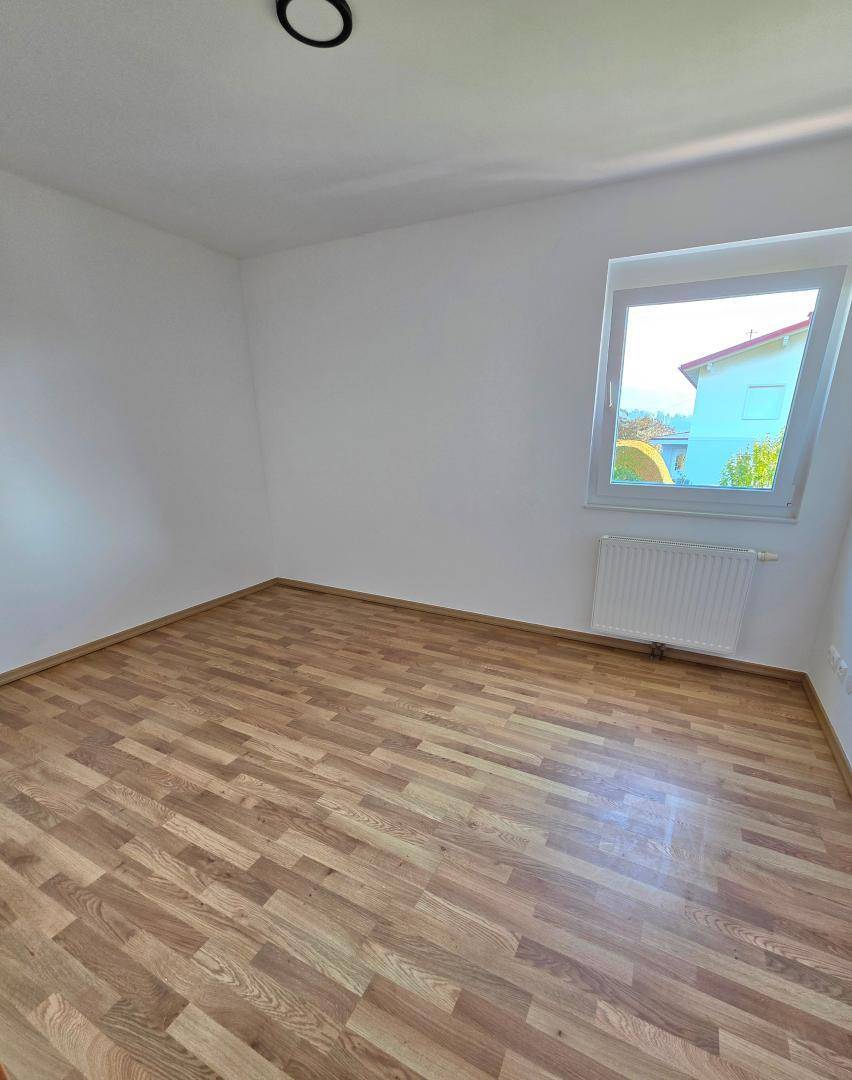 Helles Schlafzimmer mit Laminatboden und Fenster, ideal als Kinder- oder Gästezimmer.