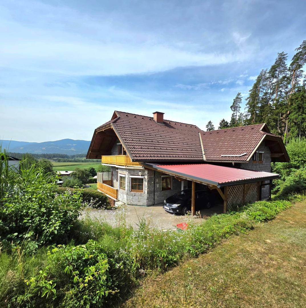 Freistehendes Haus mit Carport, Satteldach und weitem Blick in die Landschaft, umgeben von Natur.