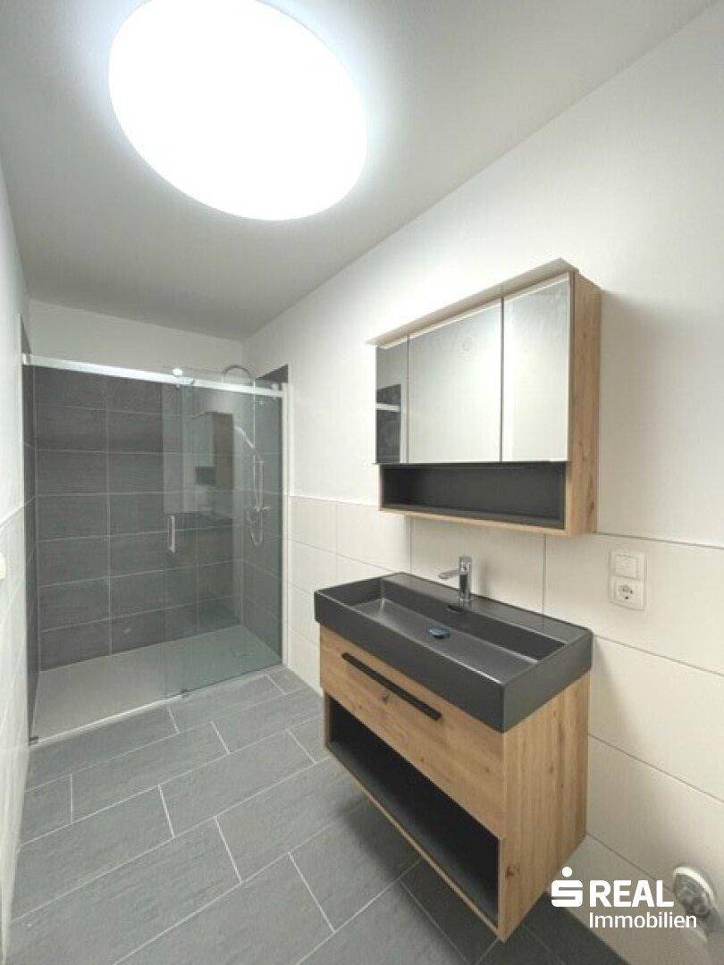 Zeitgemäßes Badezimmer mit großzügiger Dusche und stilvollem Waschtischunterschrank.
