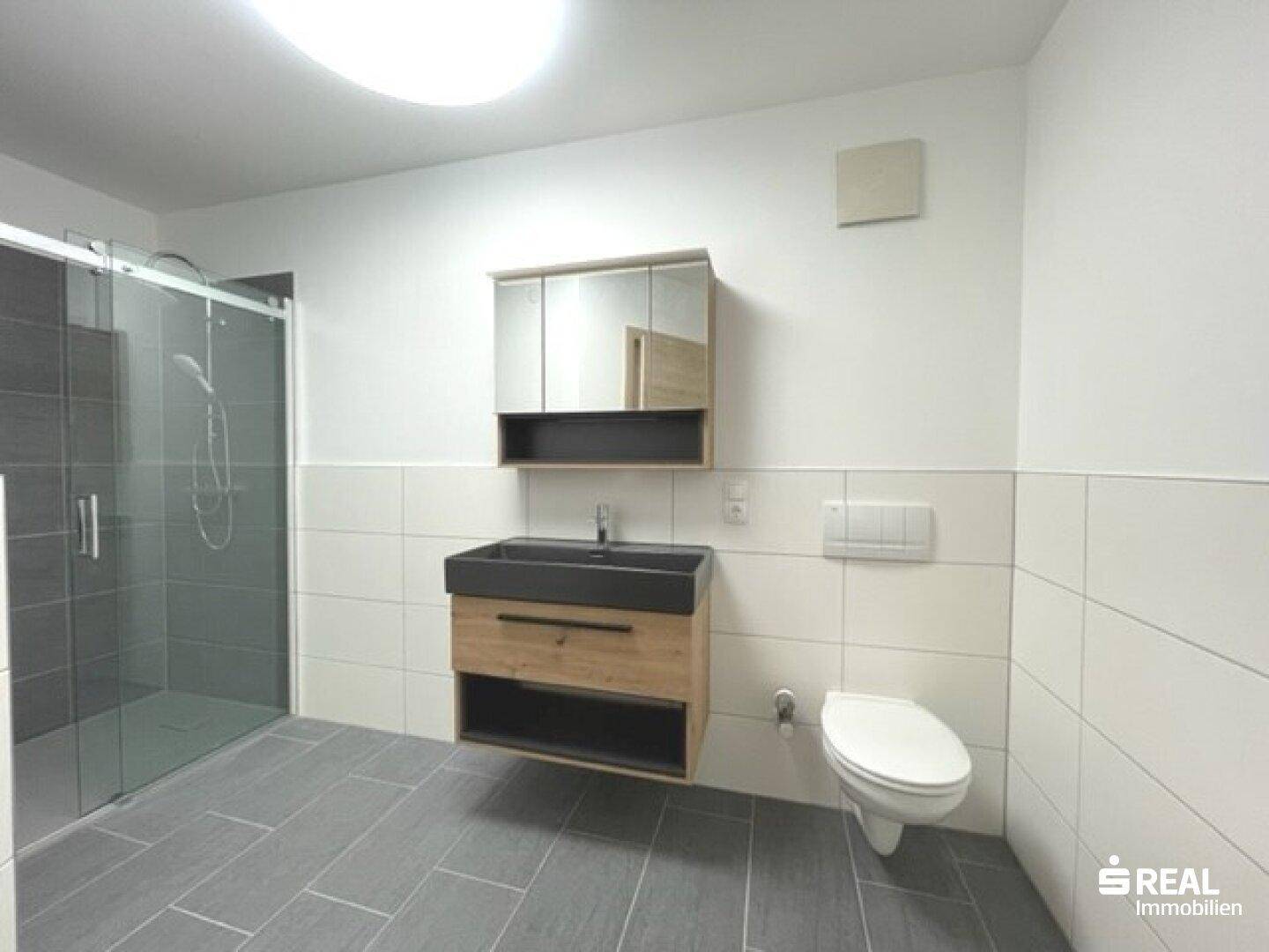 Modernes Badezimmer mit begehbarer Dusche, schwebendem Waschtisch und Wand-WC.