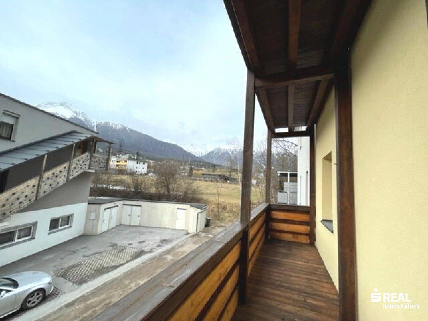 Geräumiger Balkon mit Holzboden und Geländer, bietet einen weiten Blick auf die Berge.