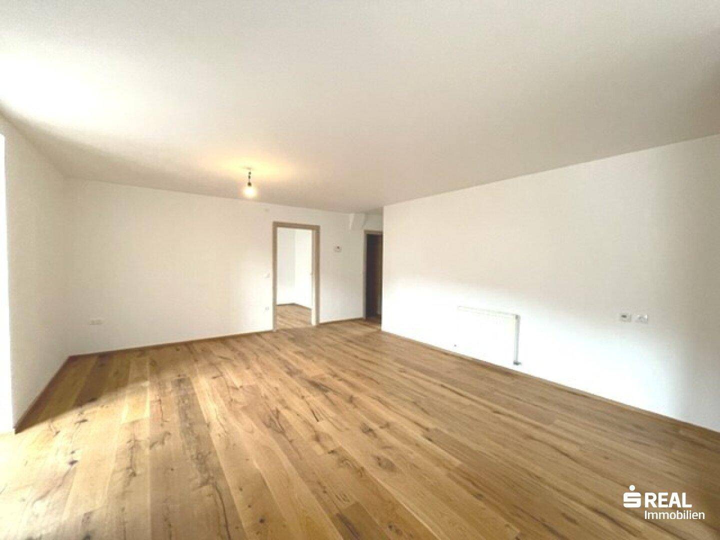 Heller und geräumiger Wohnbereich mit Holzboden und neutralen Wänden.