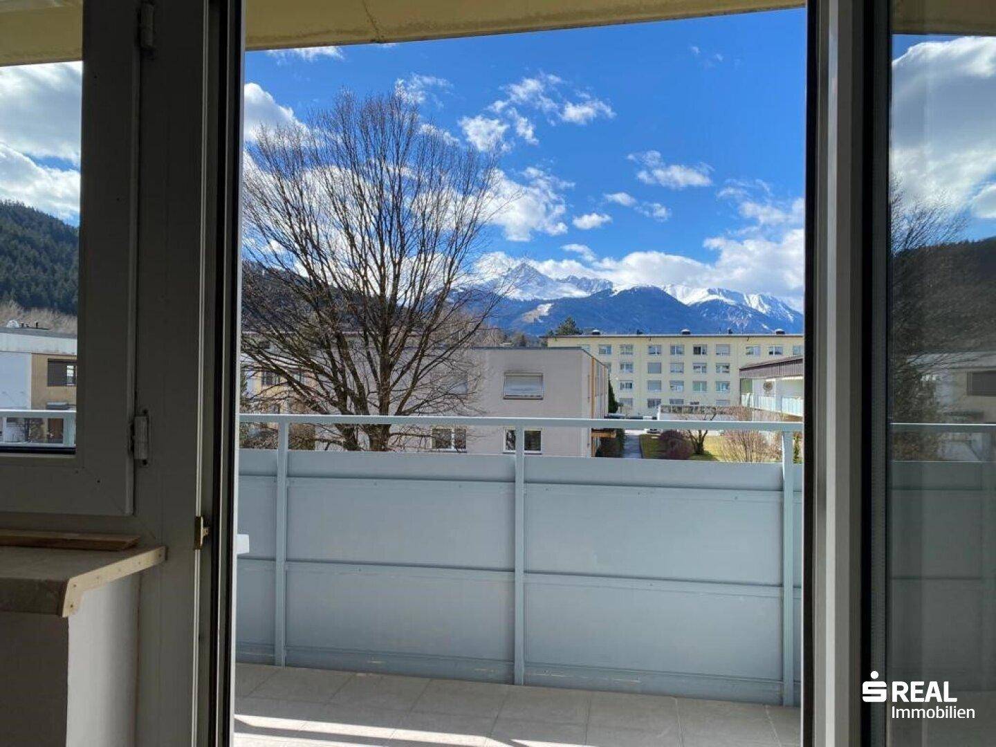 Balkon mit weitem Blick auf die umliegende Berglandschaft und die darunterliegenden Gebäude.