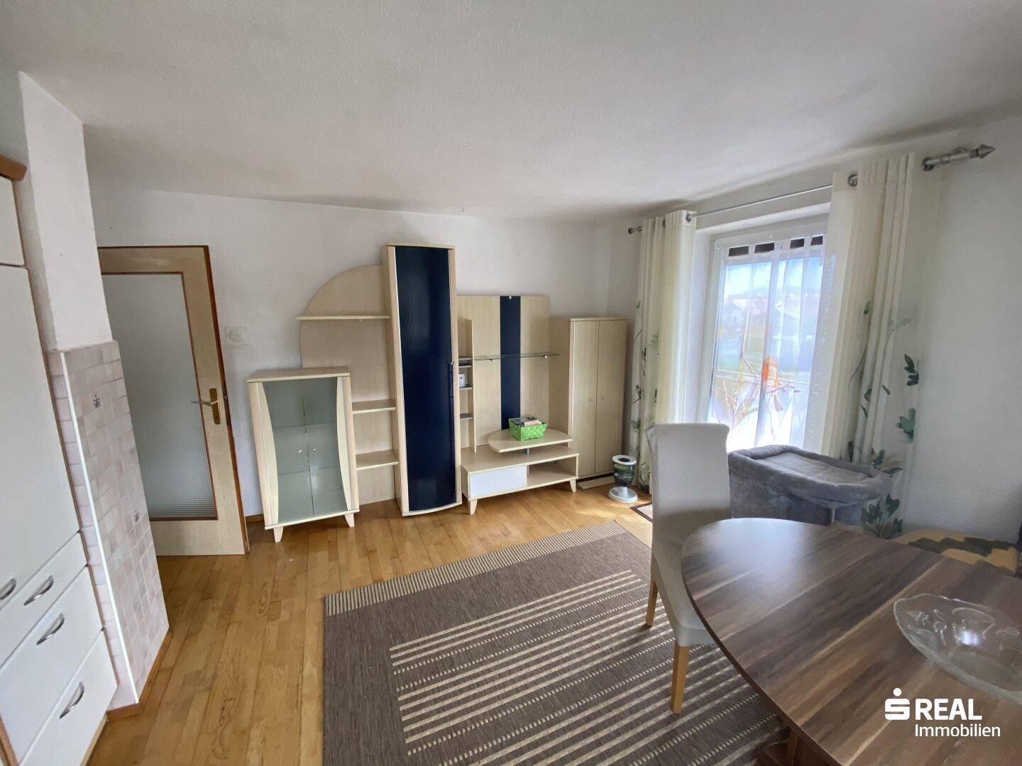 Wohnzimmer mit Holzboden, modernen Möbeln und Zugang zu einem Außenbereich.