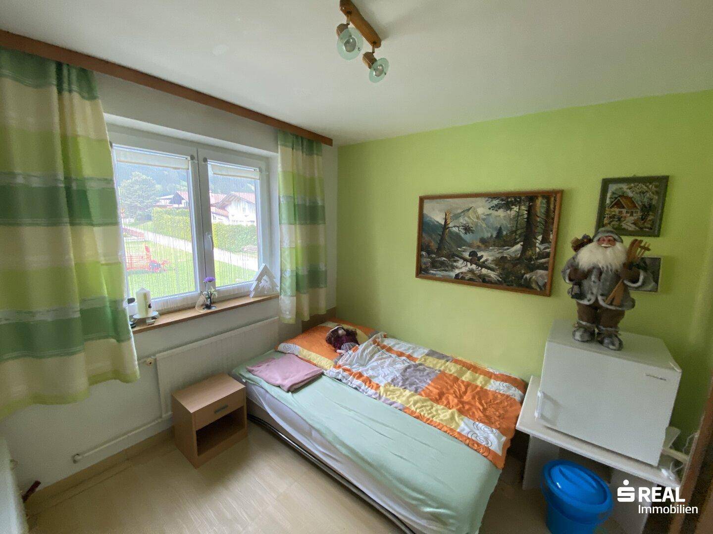 Kinderzimmer mit grün gestrichenen Wänden, Einzelbett und Blick ins Grüne.