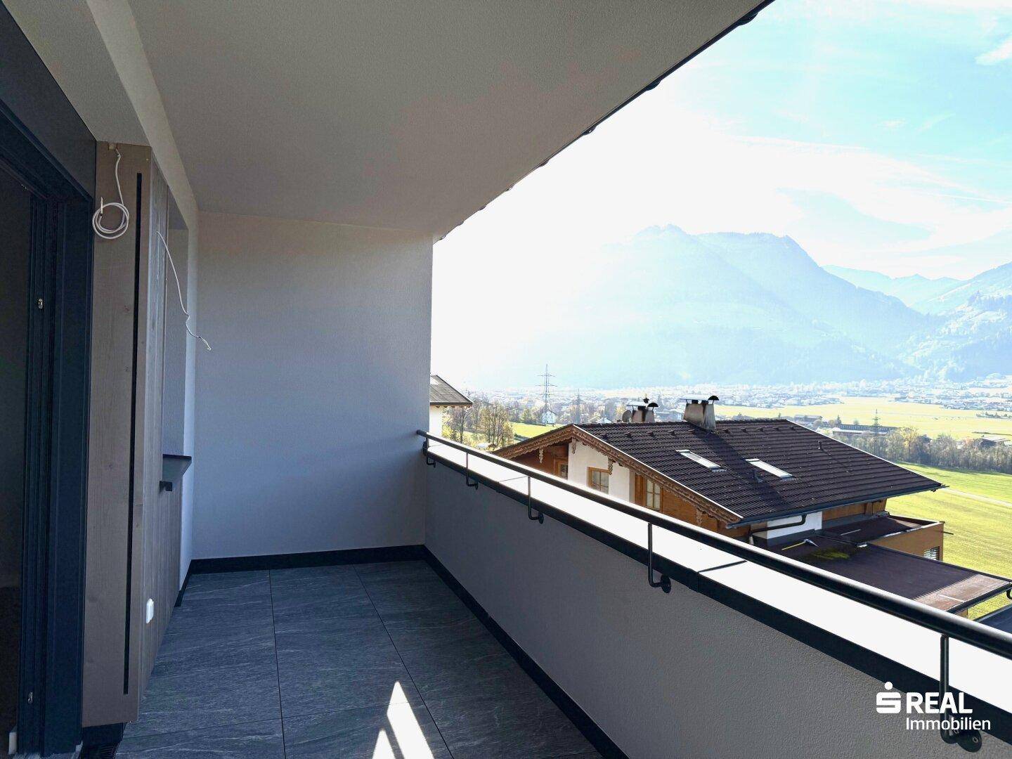 Heller Balkon mit Fliesenboden und Bergblick über das Tal an einem sonnigen Tag.