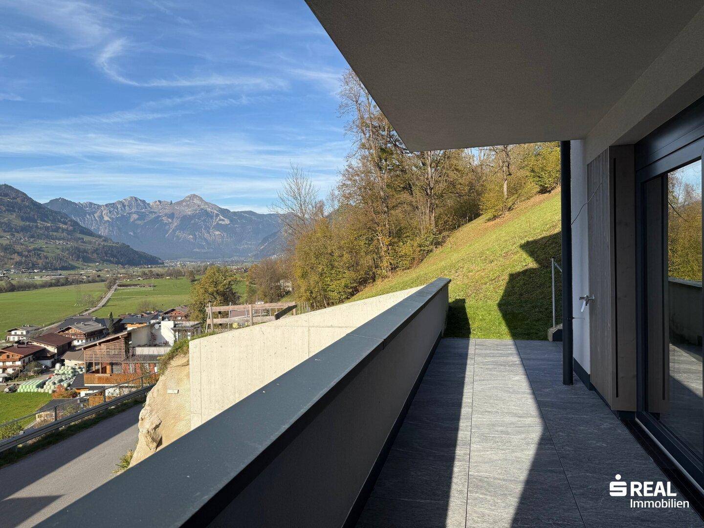Geräumiger Balkon mit Fliesenboden und beeindruckendem Weitblick auf die umliegende Berglandschaft.