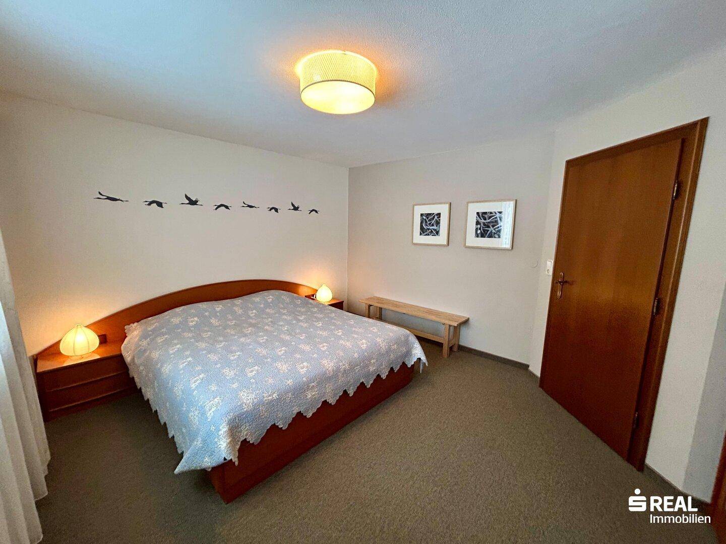 Helles Schlafzimmer mit Doppelbett, Nachttischen und schlichter Wanddekoration.