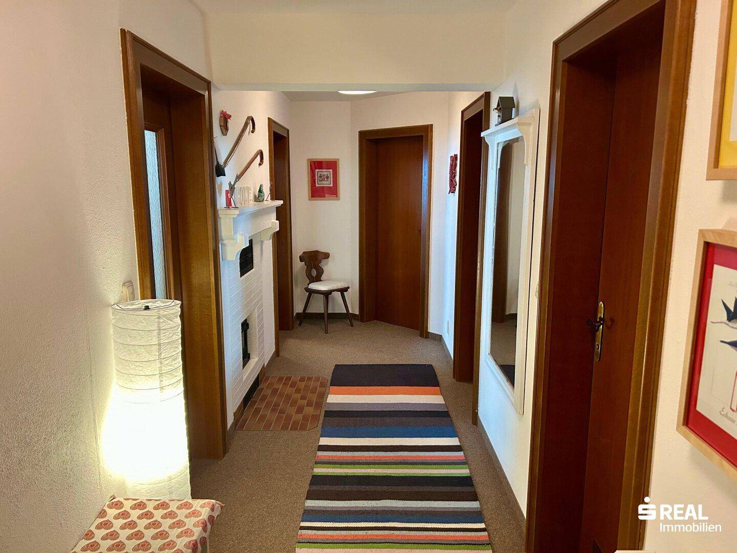 Langer Flur mit Teppichläufer, Holztüren und traditionellen Wanddekorationen.