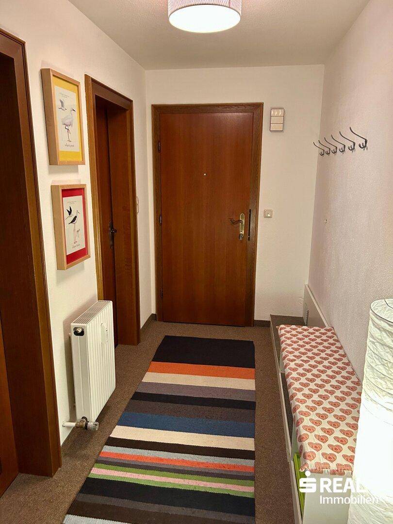 Eingangsbereich mit Garderobe, Heizkörper und farbenfrohem Teppichläufer.
