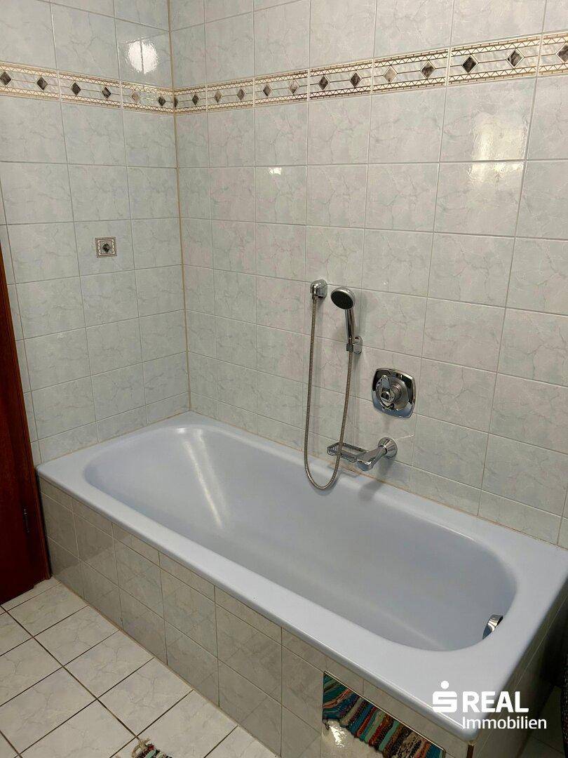 Badewanne in einem gefliesten Badezimmer mit traditionellem Design.