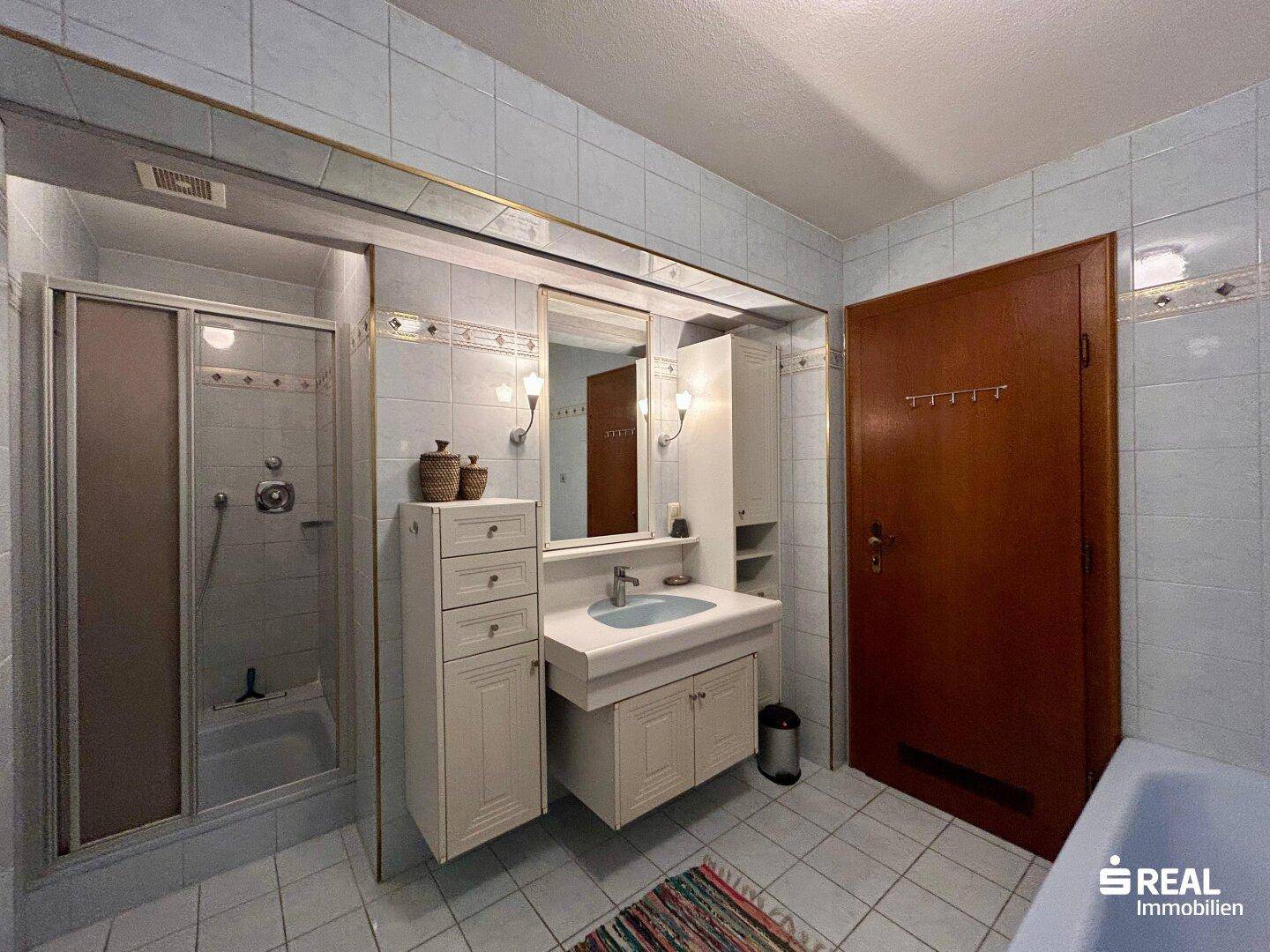 Badezimmer mit hellblauen Fliesen, Waschtisch, Dusche und Badewanne.