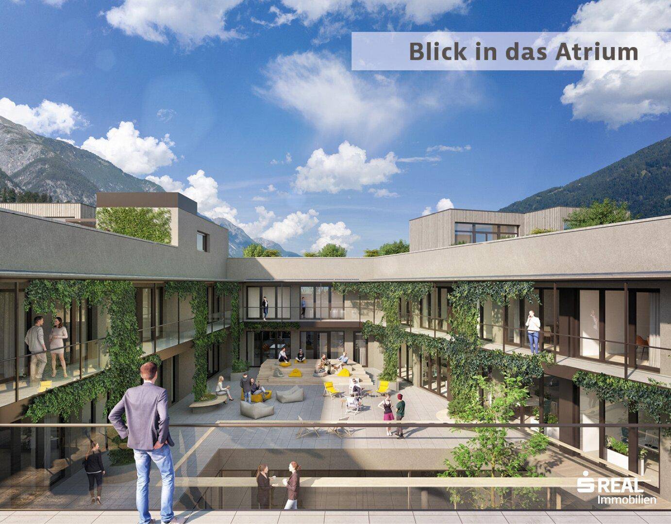 Blick in das begrünte Atrium mit Sitzgelegenheiten und umlaufenden Balkonen.