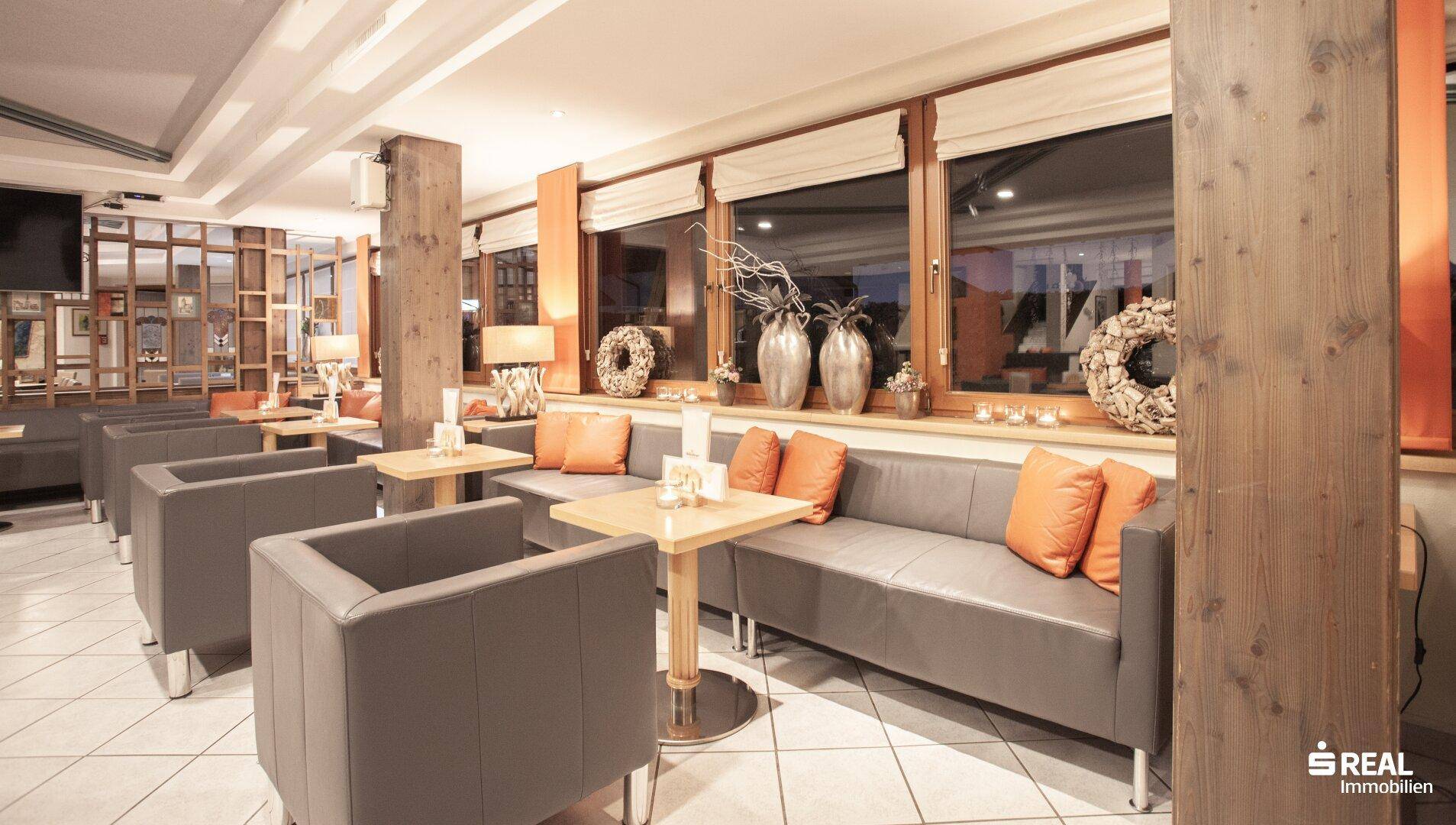 Gemütliche Hotellounge mit bequemen Sitzgelegenheiten, Holzelementen und großen Fenstern.