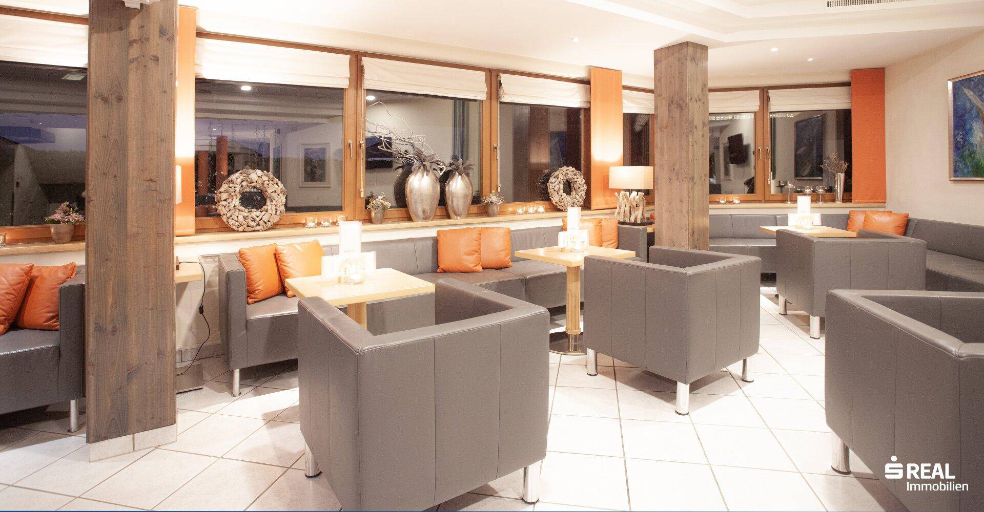 Gemütliche Hotellounge mit bequemen Sitzgelegenheiten, Holzelementen und großen Fenstern.