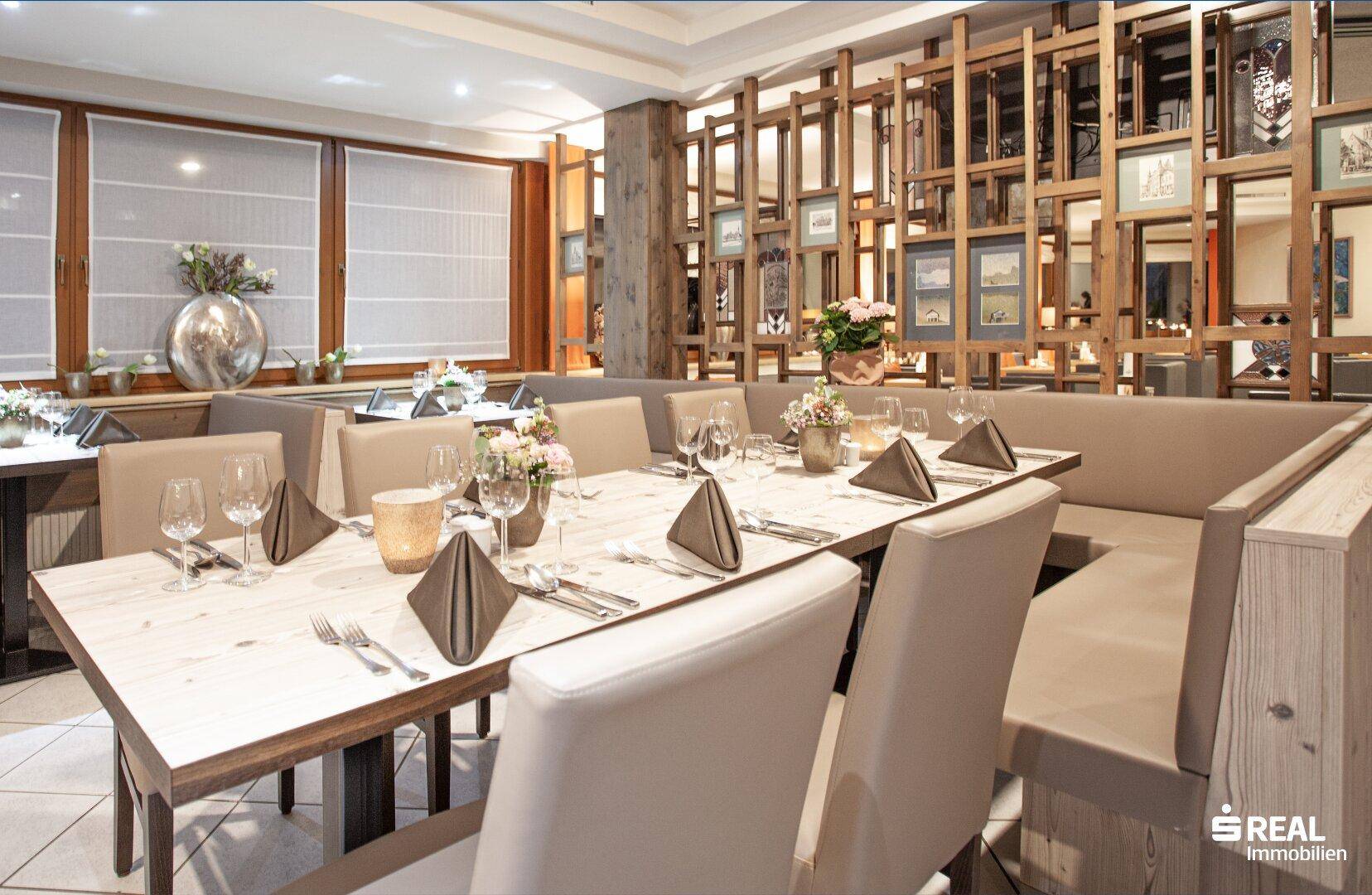 Restaurantbereich mit Holzelementen, gedeckten Tischen und bequemen Sitzbänken.