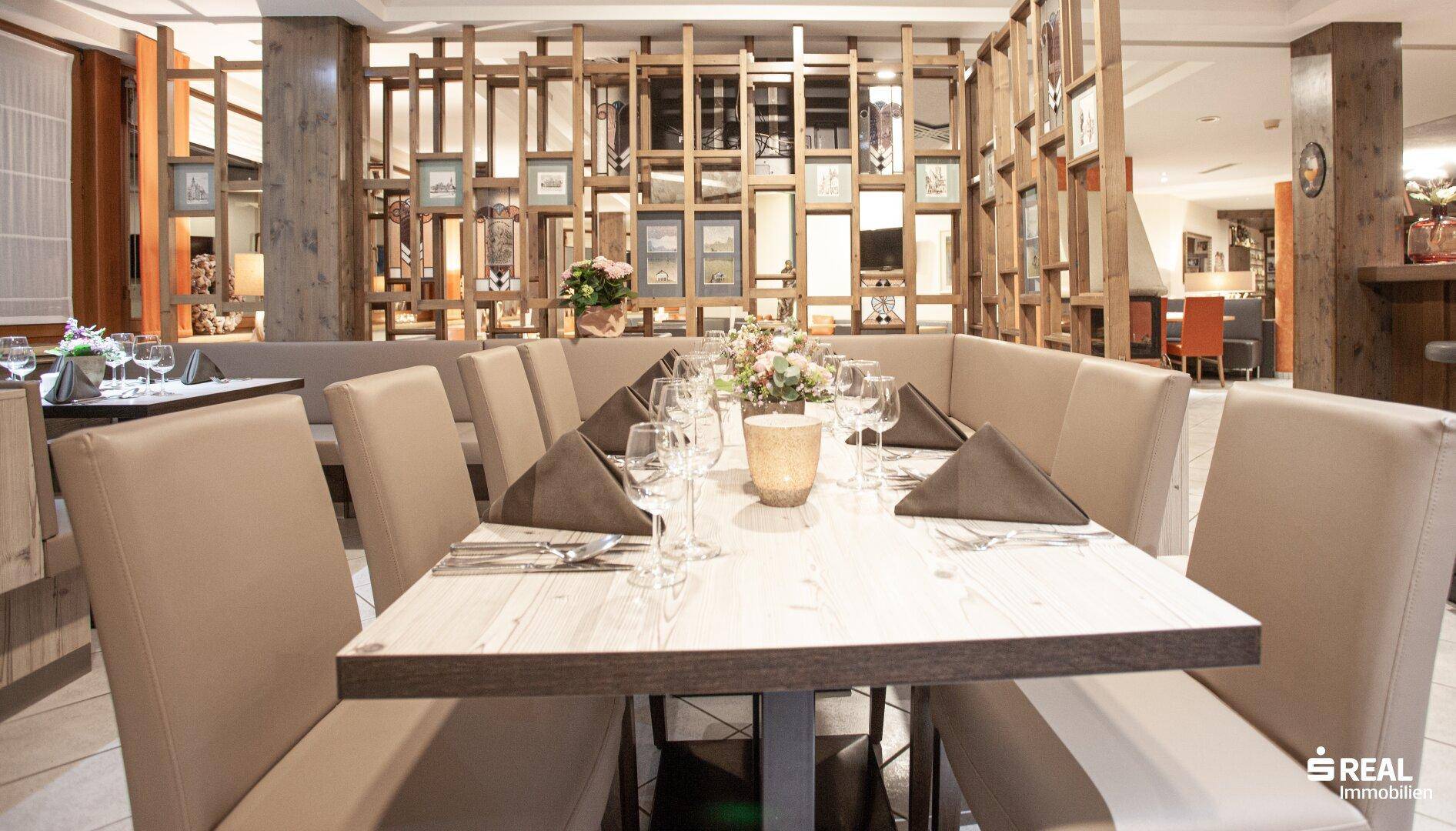 Restaurantbereich mit Holzelementen, gedeckten Tischen und bequemen Sitzbänken.