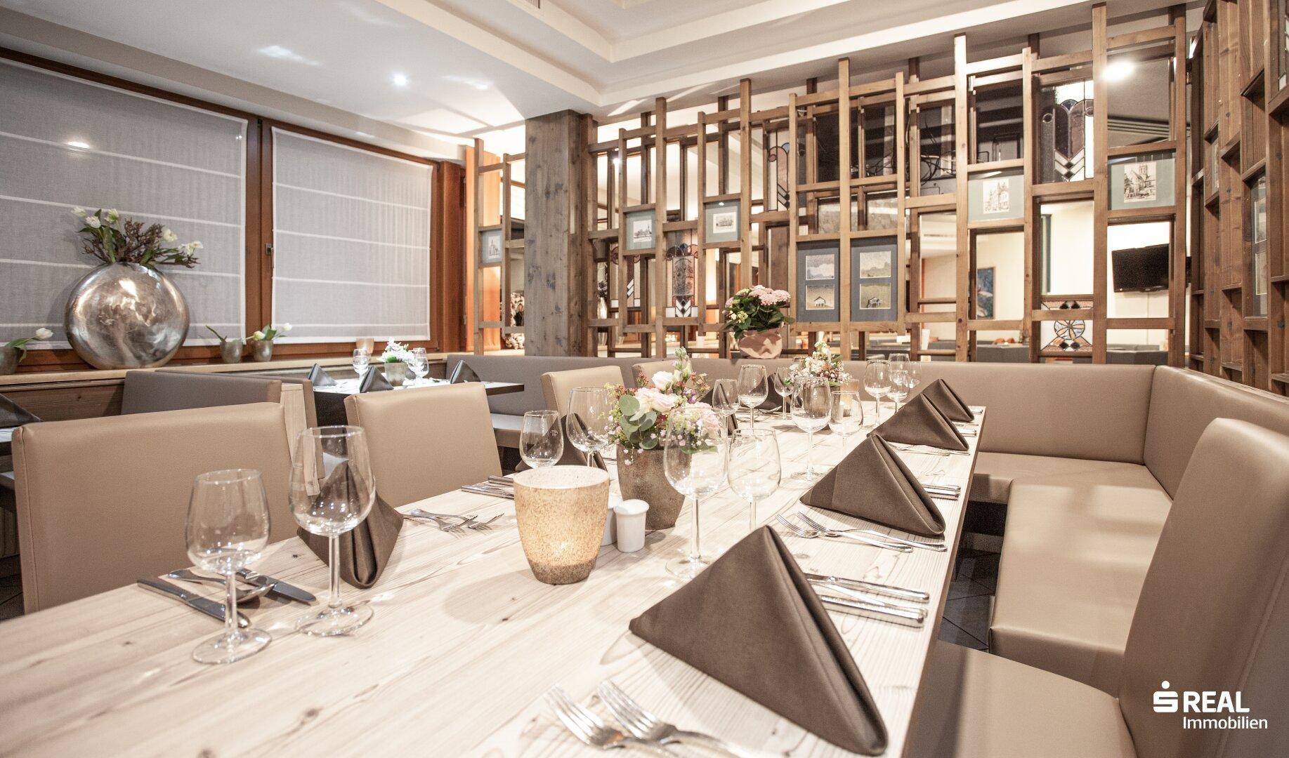 Restaurantbereich mit Holzelementen, gedeckten Tischen und bequemen Sitzbänken.