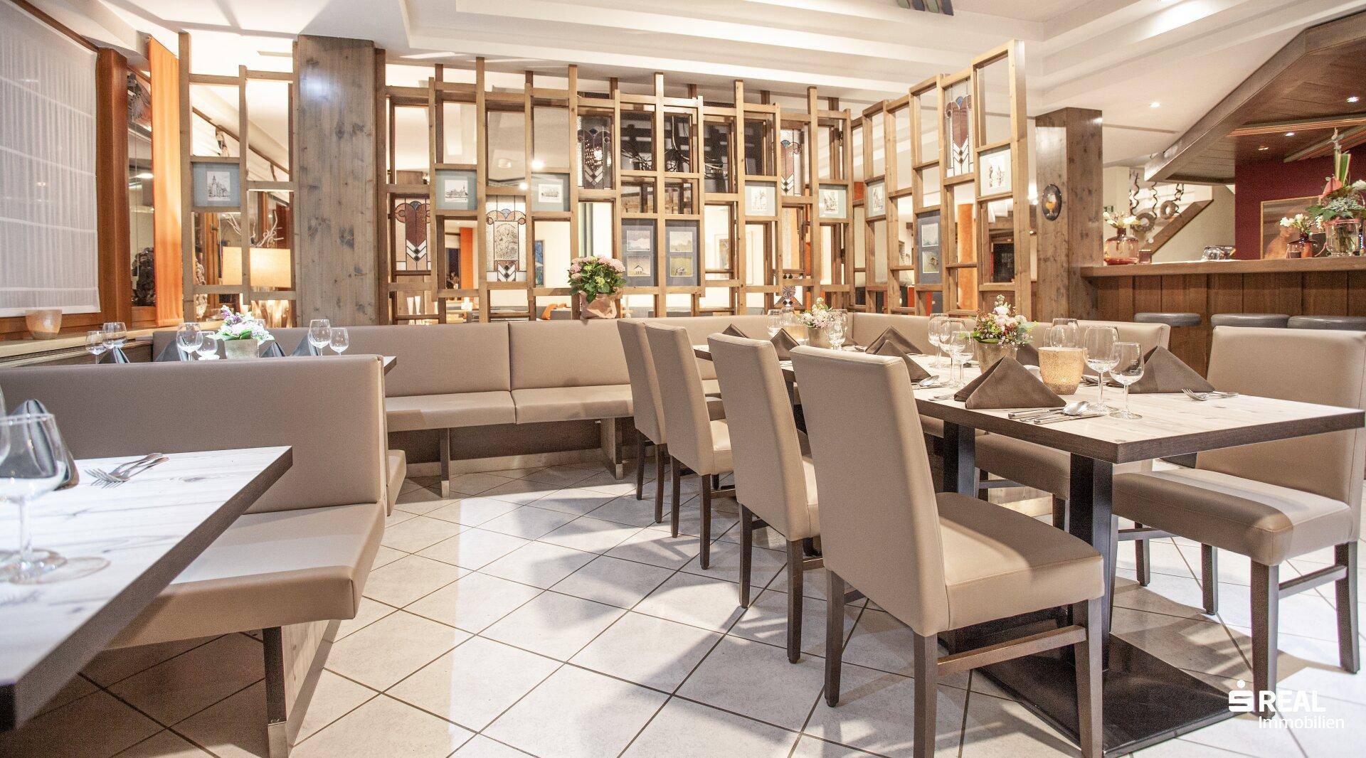 Restaurantbereich mit Holzelementen, gedeckten Tischen und bequemen Sitzbänken.