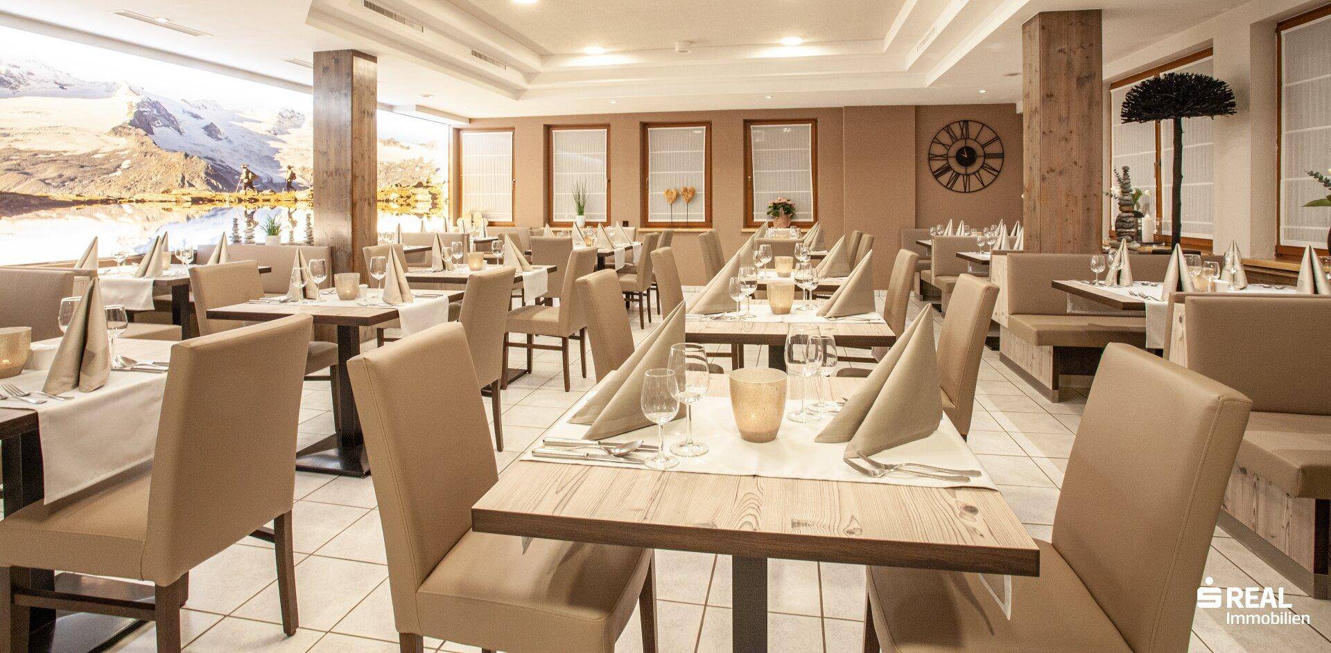 Elegantes Restaurant mit gedeckten Tischen, bequemen Stühlen und alpiner Wanddekoration.