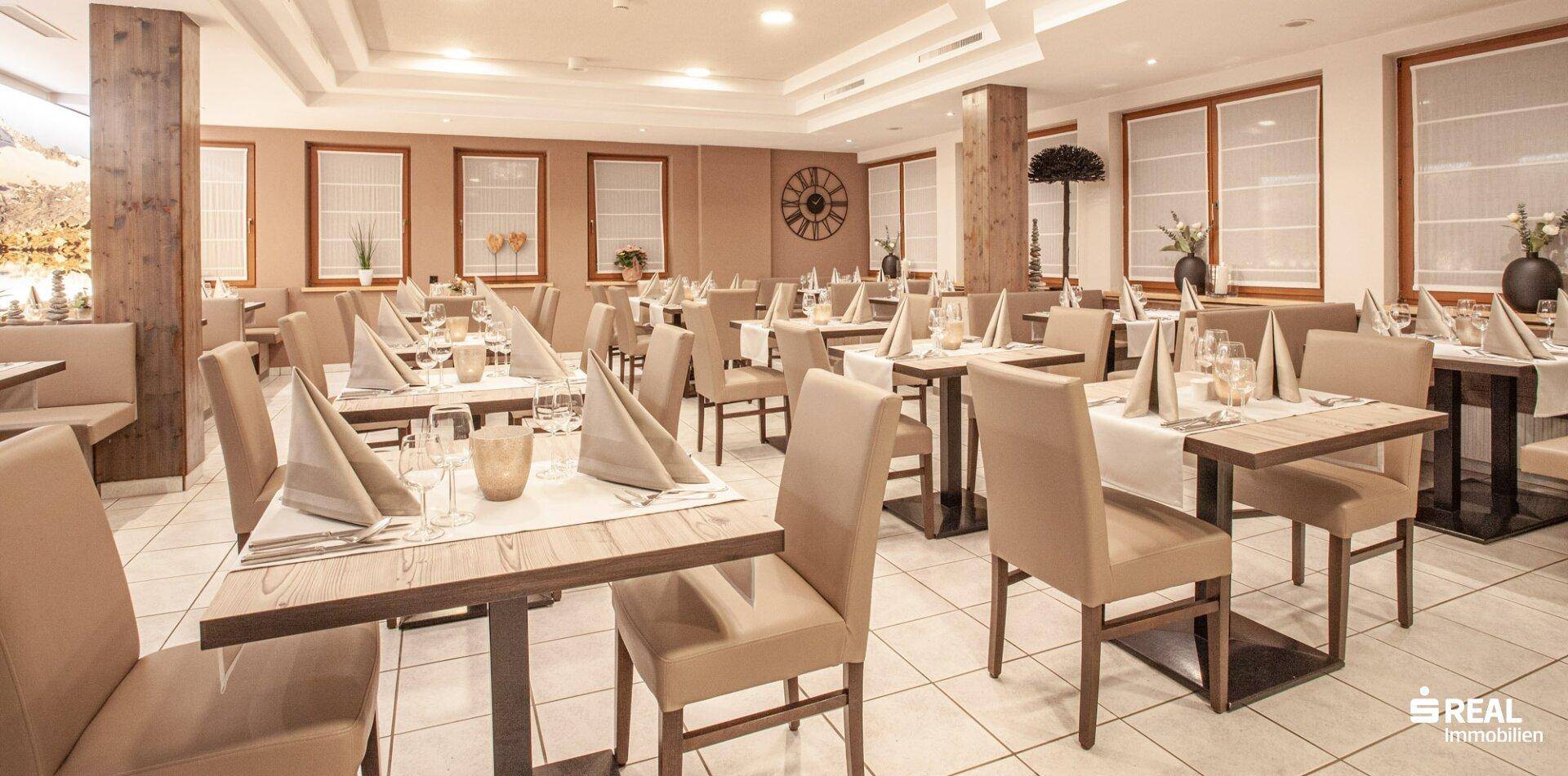 Elegantes Restaurant mit gedeckten Tischen, bequemen Stühlen und alpiner Wanddekoration.