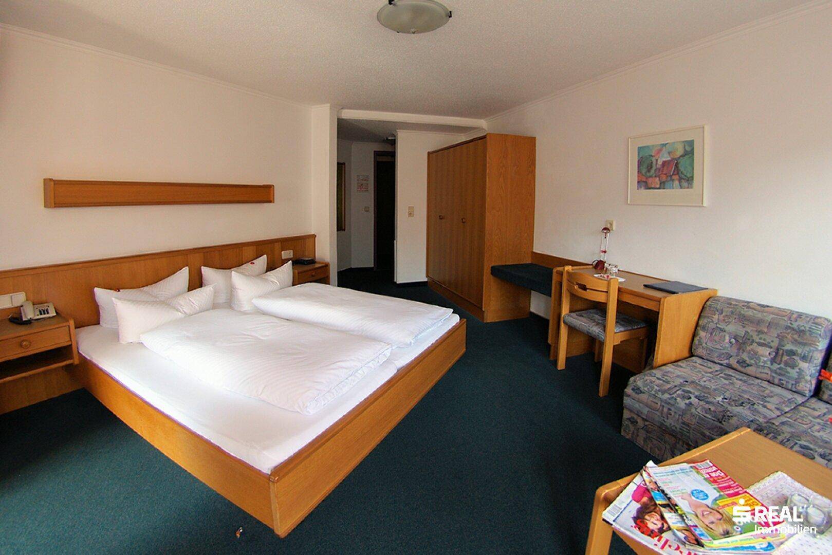Geräumiges Schlafzimmer mit Doppelbett, Kleiderschrank, Schreibtisch und Sitzgelegenheit.