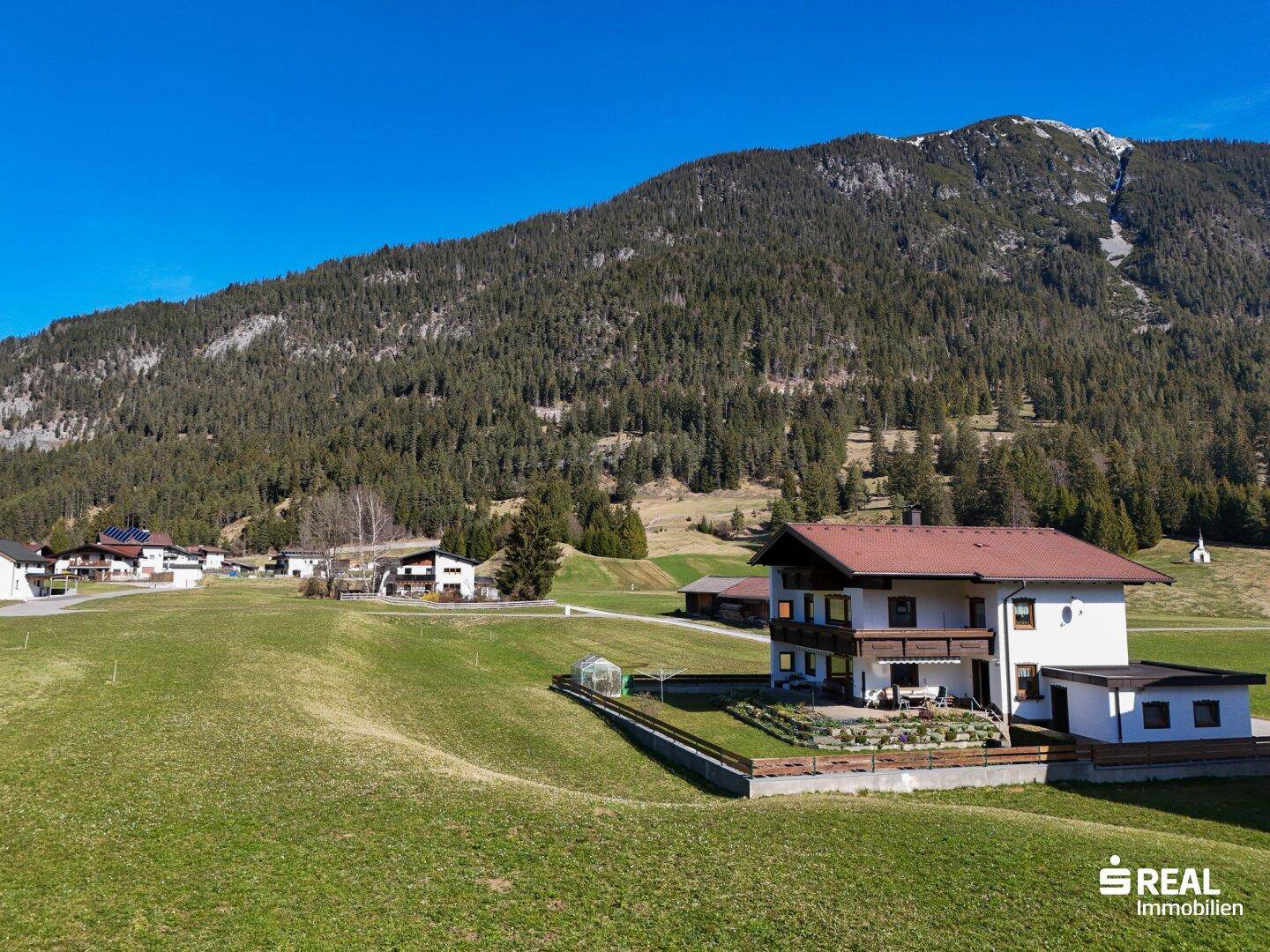 Traditionelles Haus in alpiner Landschaft mit Bergblick und weitläufigen Grünflächen.