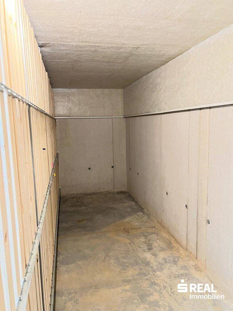 Geräumiger Abstellraum im Kellerbereich mit unverputzten Wänden und Betonboden.