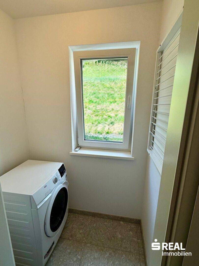 Praktischer Hauswirtschaftsraum mit Waschmaschine und Fenster für natürliche Belüftung.