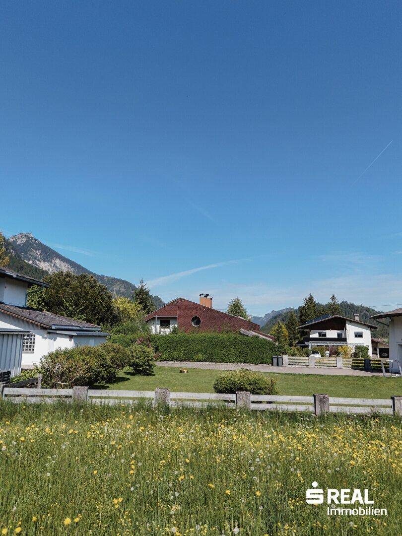 Wohngebiet mit gepflegten Gärten und einer malerischen Bergkulisse, ideal für Naturliebhaber.