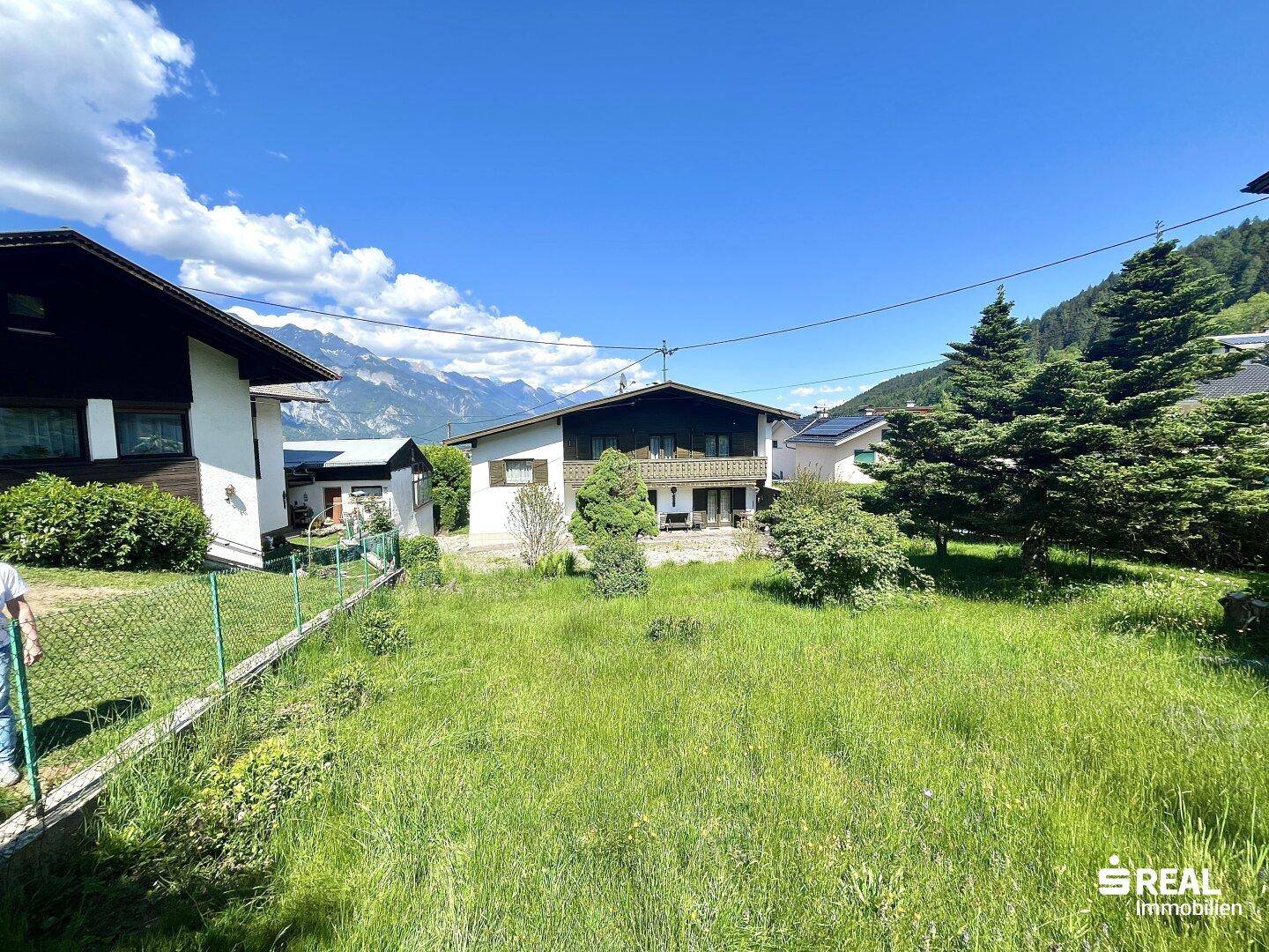 Großer, gepflegter Gartenbereich mit Rasenfläche und Blick auf das Haus und die Berge.