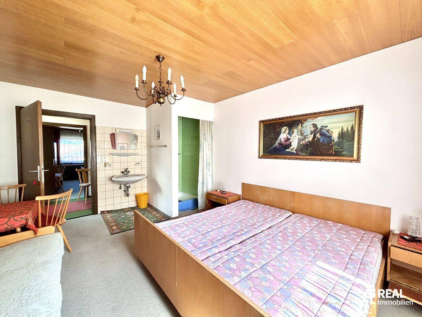 Schlafzimmer mit Doppelbett, integriertem Waschbecken und separater Duschkabine.