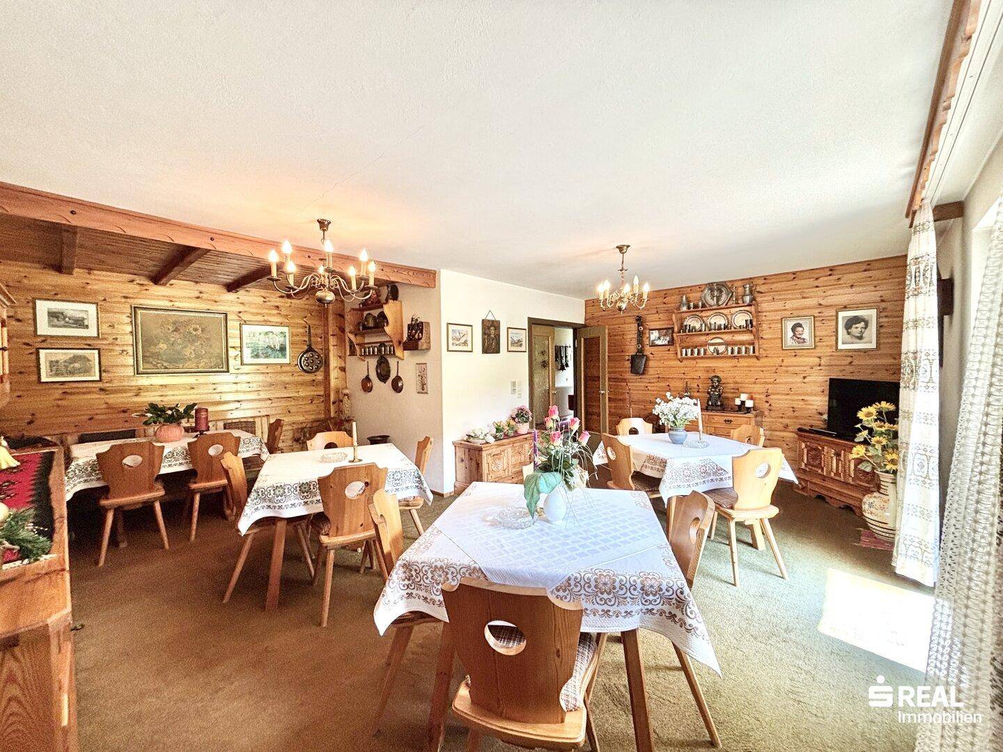 Traditioneller Speisesaal mit holzgetäfelten Wänden, mehreren Tischen und rustikalem Charme.