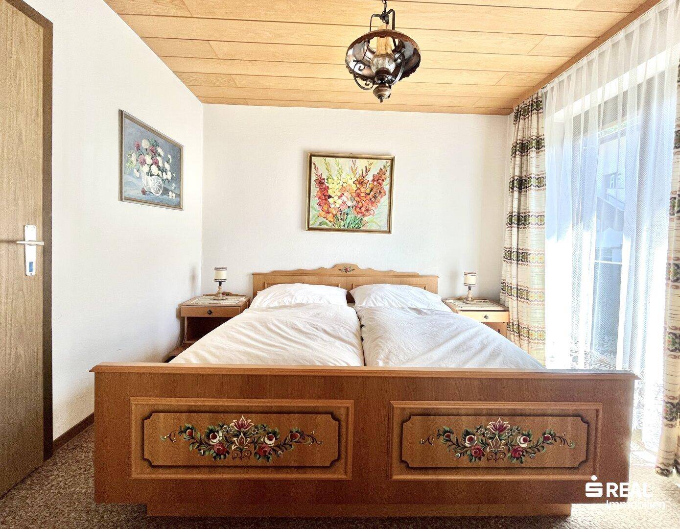 Schlafzimmer mit traditionellem, kunstvoll geschnitztem Holzdoppelbett und Holzdecke.