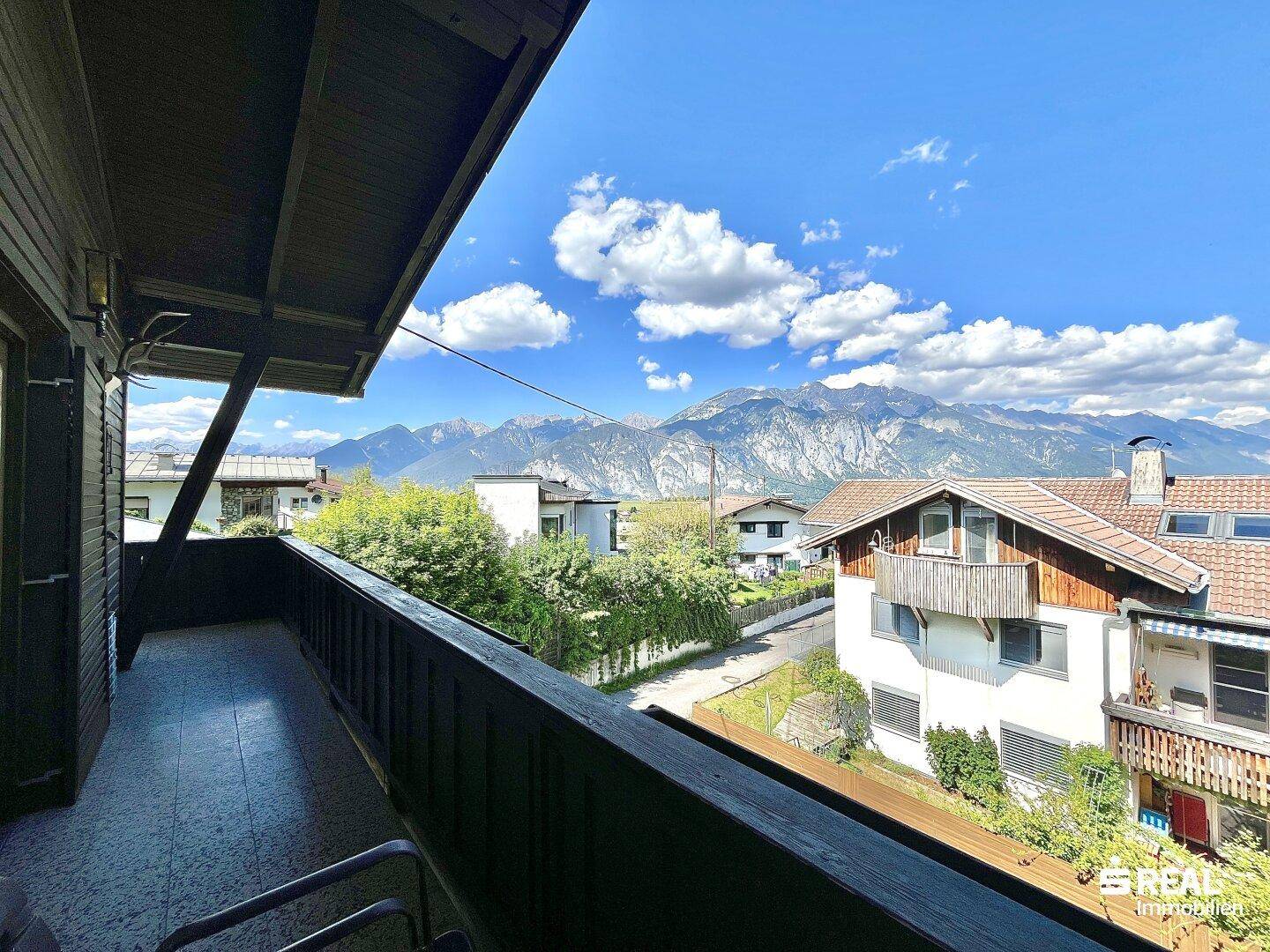 Geräumiger Balkon mit Holzboden und atemberaubendem Blick auf die umliegende Berglandschaft.
